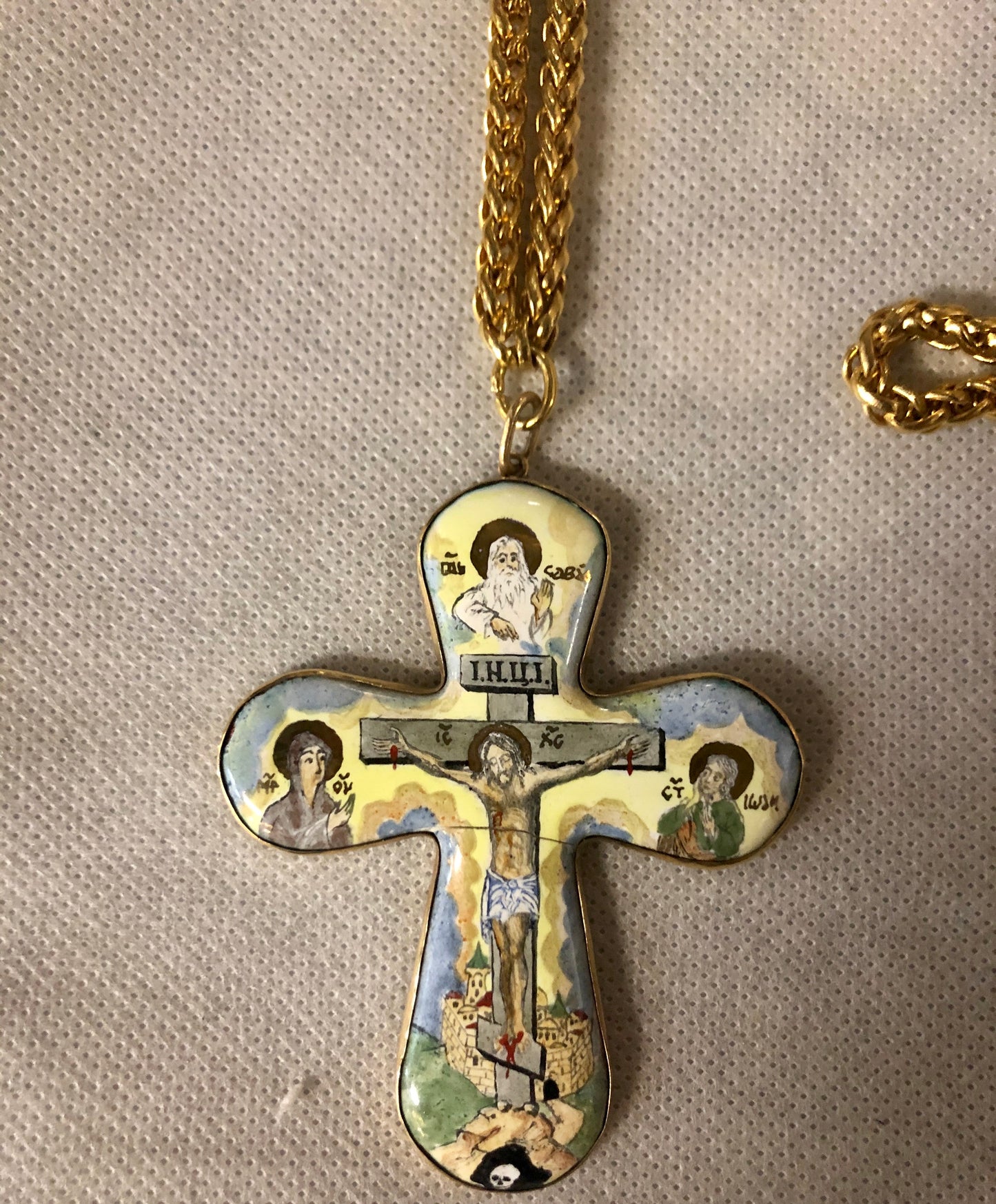 A porcelain Cross, depicting Jesus’s crucifixion. 14K gold.